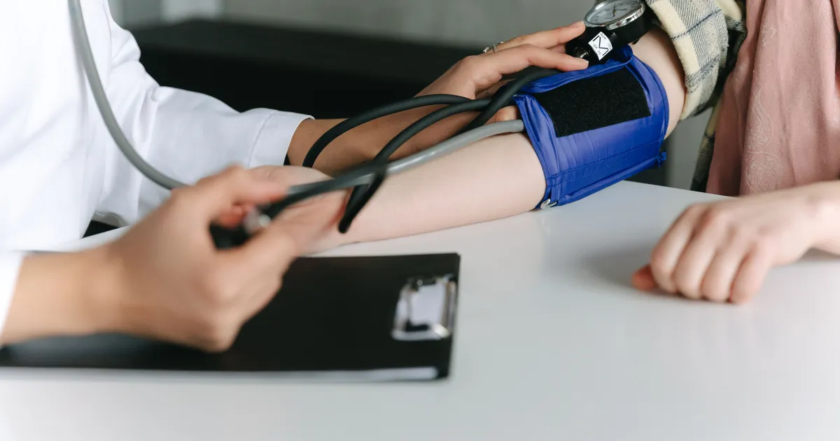 Personal de salud toma la presión arterial a un paciente durante un examen médico en consultorio