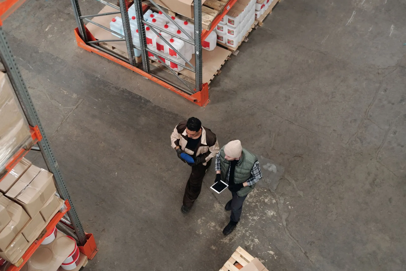 Vista cenital de dos personas recorriendo el almacén de una planta, una de ellas con una tablet